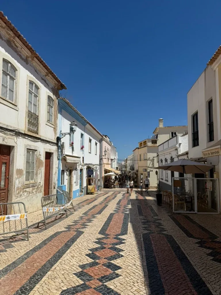 Pedestrian street in Lagos with patterned black, white and red stone paving between buildings.